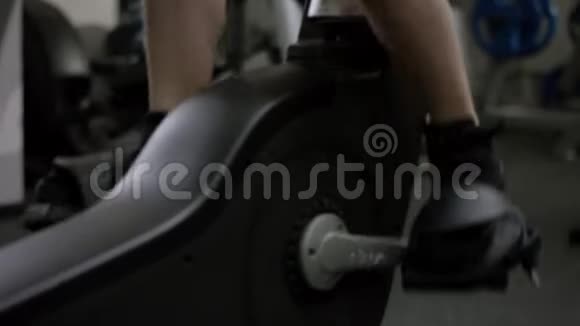 穿黑色运动衫的漂亮女孩很难在运动自行车上工作在新的健身房里专注于腿视频的预览图