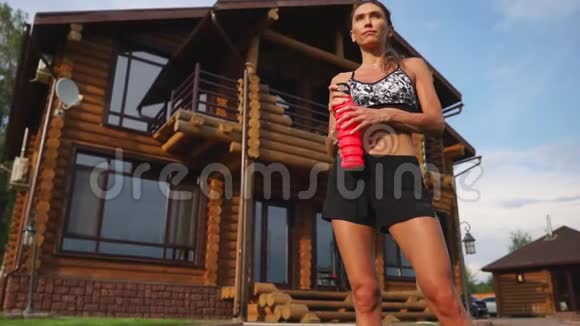 布鲁内特在她家后院接受有氧训练后感到疲倦喝着一瓶水视频的预览图