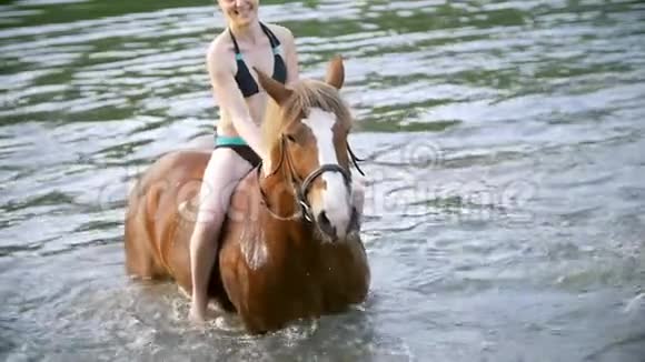 快乐的年轻女子骑马在河里玩视频的预览图