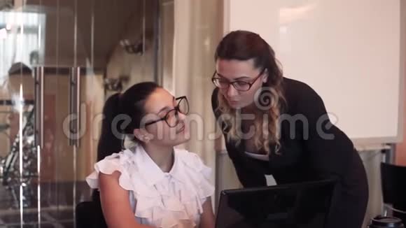特写镜头两个年轻的女商人用电脑在办公室讨论一个商业项目视频的预览图