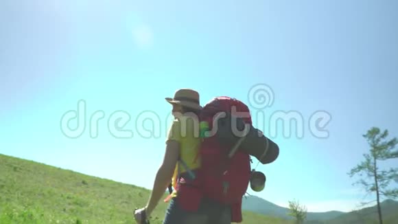 那个带着旅游棒和一个红色背包的旅行者的女人站在青山旁视频的预览图