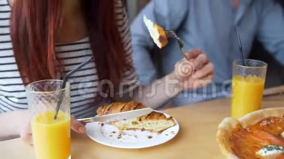 年轻女子在餐馆里用刀叉切美味的牛角面包视频的预览图