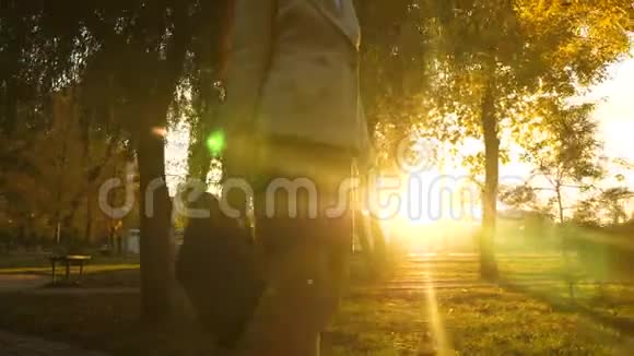 女人手里拿着公文包在阳光明媚的公园里沿着人行道走着特写镜头视频的预览图