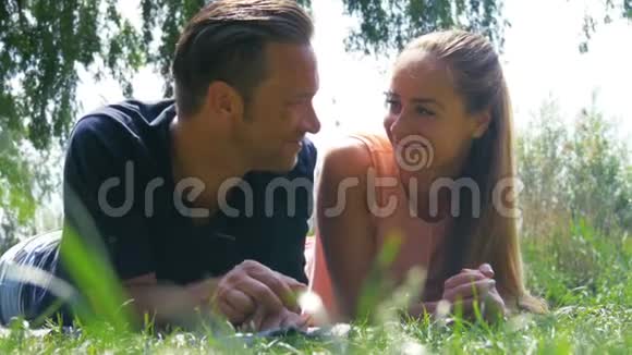 一对英俊的夫妇在公园里不寒而栗吹蒲公英视频的预览图