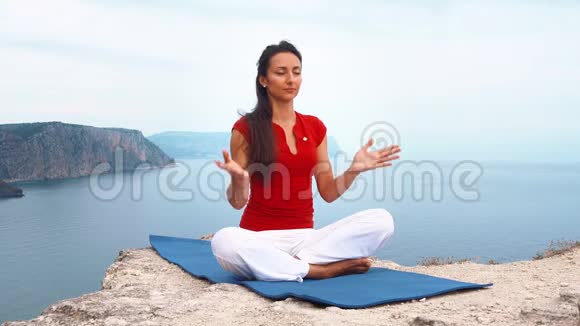 女孩坐在海边的岩石上冥想莲花瑜伽姿势集中注意力放松心灵灵魂和身体视频的预览图
