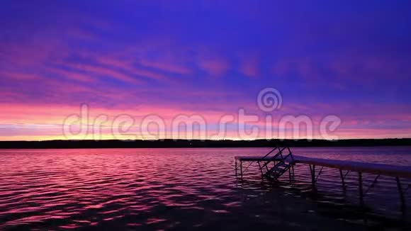 在纽约州银湖的平静的水面上有着生动的紫罗兰色日落视频的预览图