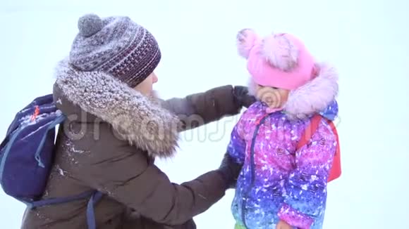 妈妈和她三岁的女儿妈妈帮一个漂亮的小宝宝脱背包视频的预览图