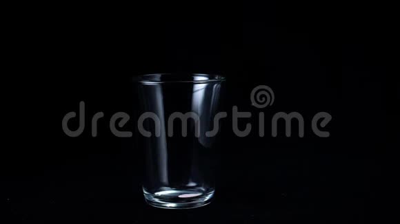 草莓奶昔分离在黑色背景上在透明玻璃中在黑色背景上倒入粘稠的粉红色奶昔视频的预览图