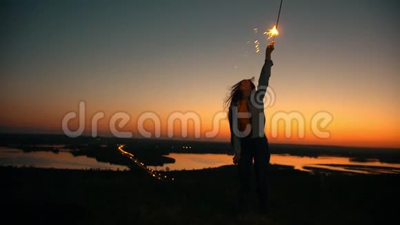 年轻女子在山上惊人的夕阳下举起手来视频的预览图