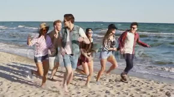 一群年轻的时髦朋友一起在水边的海滩上奔跑慢镜头视频的预览图