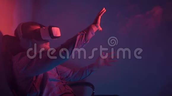 一个年轻人坐在椅子上使用VR耳机和耳机与虚拟现实互动坐在椅子上视频的预览图