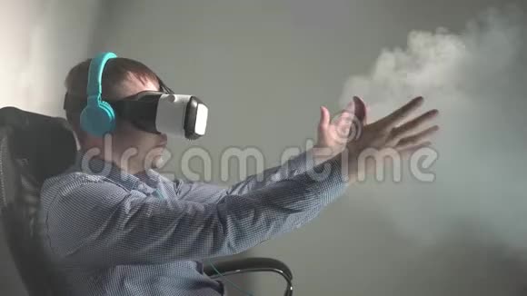 一个年轻人坐在椅子上使用VR耳机和耳机与虚拟现实互动坐在椅子上视频的预览图
