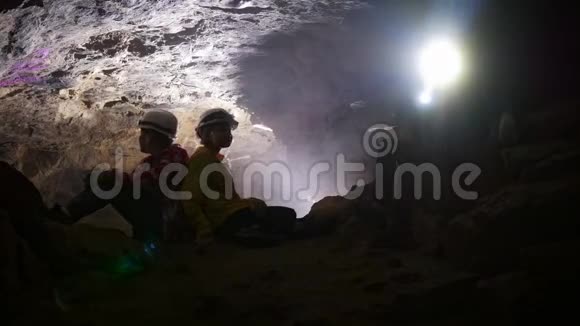 孩子们在洞穴里休息十几岁的孩子戴着头盔和手电筒视频的预览图