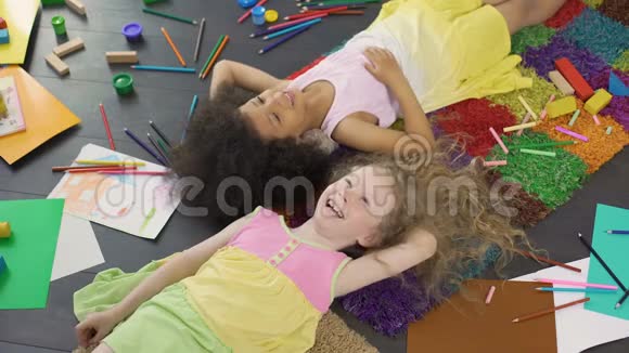 多种族的小女孩躺在地上笑着享受节日视频的预览图