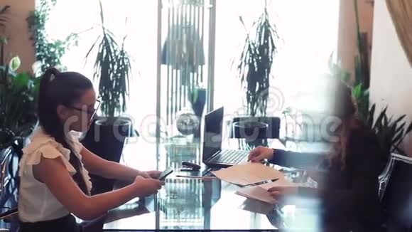 两个商务女性在办公室里坐在一张桌子旁用一个视频的预览图