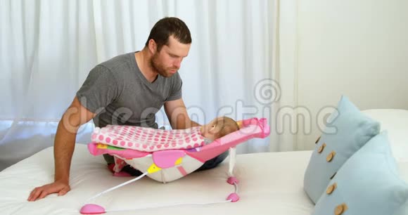 父亲把孩子放在婴儿床上睡觉视频的预览图
