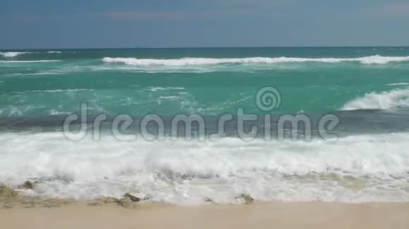 海浪在蔚蓝的天空下缓缓地在热带海滩上翻滚视频的预览图
