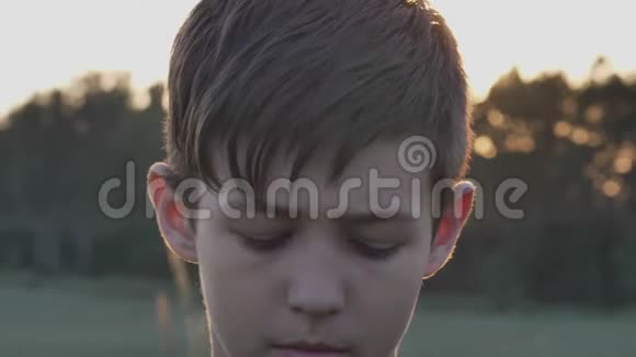 日落时分在麦田里看镜头的悲伤男孩的肖像视频的预览图