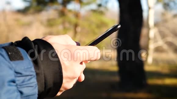 一个男人在寒冷季节穿着暖和的衣服用他的手使用他的智能手机特写镜头视频的预览图