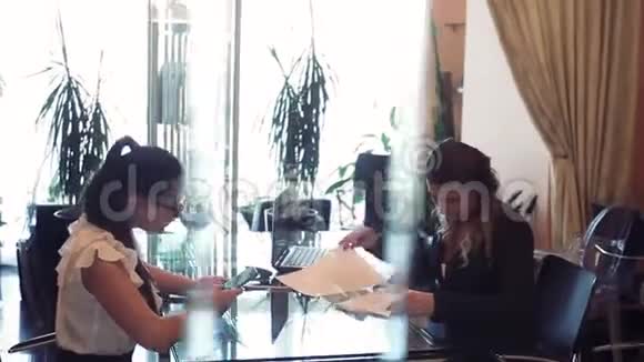 两个商务女性在办公室里坐在一张桌子旁用一台手机讨论一个商务项目视频的预览图