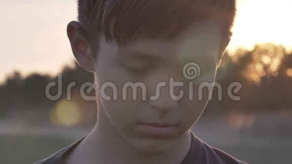 日落时分在麦田里看镜头的悲伤男孩的肖像视频的预览图