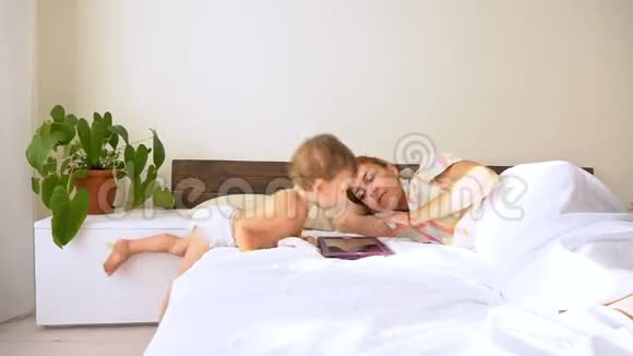 妈妈和儿子在卧室里看平板电脑视频的预览图