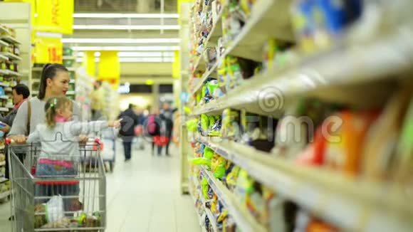 微笑的女人和女孩在食品店挑选产品的肖像妈妈和女儿把一些东西放在篮子里视频的预览图