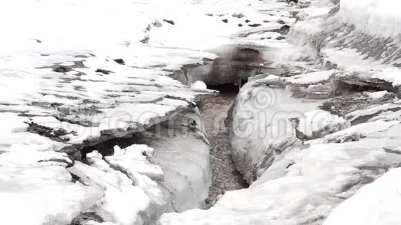 泉溪流淌在灰色的冰块之间视频的预览图