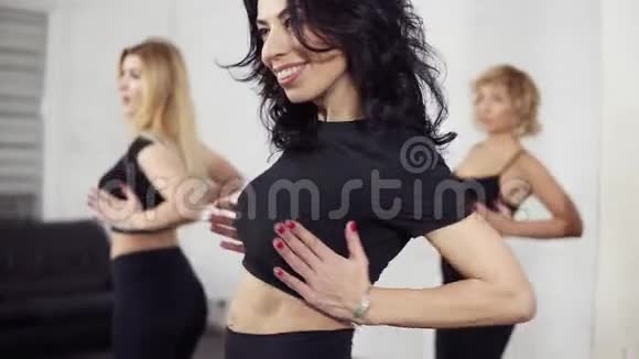 有吸引力的女性舞者在学习巴切塔动作时滚动和扭动视频的预览图