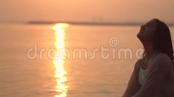 在日落时快乐的女孩站在河里背对着太阳慢动作特写镜头高清快乐视频的预览图