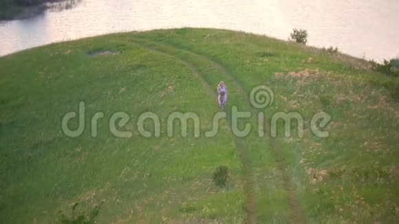 鸟瞰可爱的女孩和妈妈在河边的夏日草地上跑步很开心视频的预览图