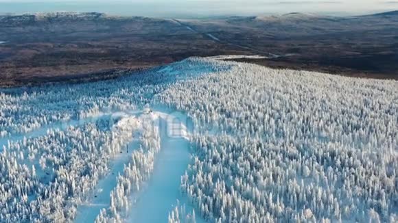 冬季森林和缆车小屋环绕的滑雪道的鸟瞰图从上面看视频的预览图