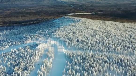 冬季森林和缆车小屋环绕的滑雪道的鸟瞰图从上面看视频的预览图