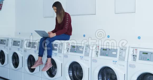 女人坐在洗衣机里用笔记本电脑视频的预览图