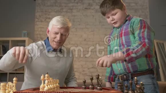 爷爷和孙子正准备下棋一个老人教一个胖孩子如何下棋暴露在视频的预览图