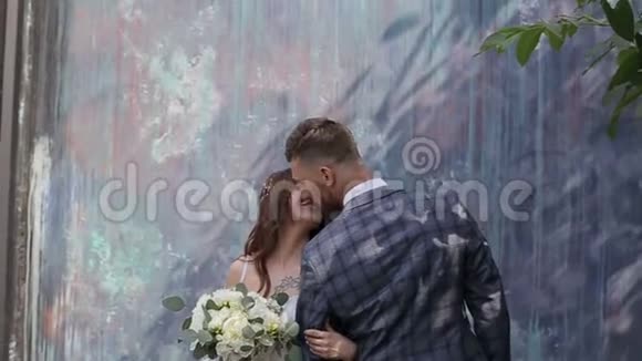 结婚那天一对漂亮的夫妇在有趣的墙边接吻视频的预览图