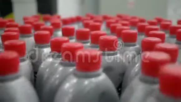 装有液体的红色盖子的塑料瓶在工厂室内的传送带上绕圈移动视频的预览图