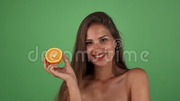 摄影棚拍摄的一个美丽快乐的女人微笑着拿着半个橘子视频的预览图