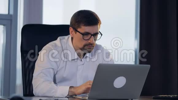 一个快乐的商人在笔记本电脑前工作高兴地微笑着视频的预览图