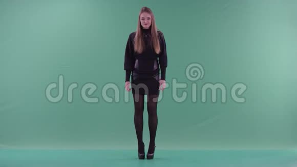 穿着黑色便服的年轻美女站在绿色屏幕前听音乐跳舞视频的预览图