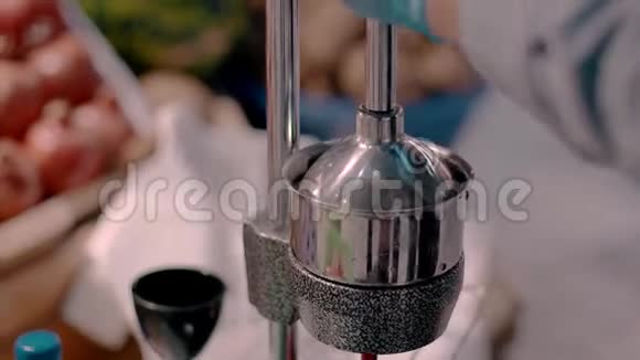一个戴手套的人用机械榨汁机从水果中榨出果汁特写过程视频的预览图