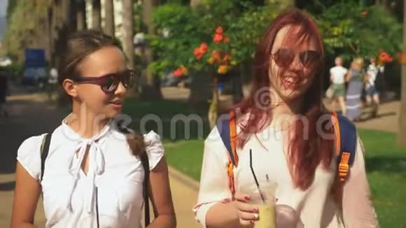 两个女孩在外面散步时交谈和喝鸡尾酒4K慢镜头拍摄视频的预览图