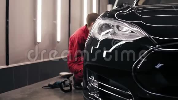汽车中心工人做最后擦拭完美抛光的新黑色汽车视频的预览图