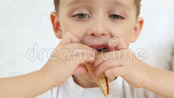 一个孩子很高兴在一个华夫饼锥里吃一个巧克力冰淇淋坐在桌子上背景是白色的关闭视频的预览图