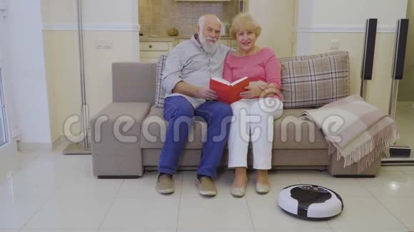 老年人手里拿着书坐在家里的沙发上照相机视频的预览图