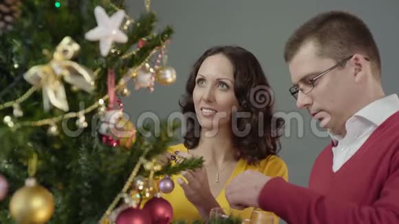 浪漫的情侣装饰圣诞树在家享受相互的消遣视频的预览图
