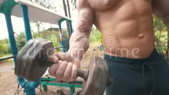 巨大的肌肉男手在户外运动公园里举起沉重的铁哑铃视频的预览图