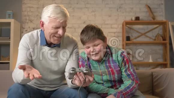 孙子教爷爷玩控制台游戏老人正在学习如何玩电子游戏他没有视频的预览图