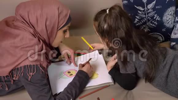 穆斯林母女躺在沙发上用彩色铅笔作画背景舒适侧视50视频的预览图
