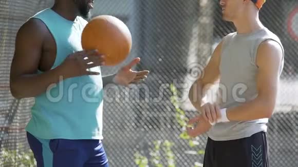 两位多种族的运动员朋友在体育场讨论最后一场篮球比赛视频的预览图